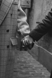 grayscale photo of man in coat holding cigarette stick