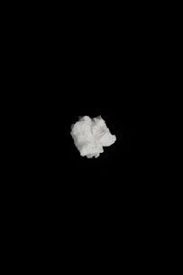 A single crumpled white tissue or paper is centered against a solid black background.