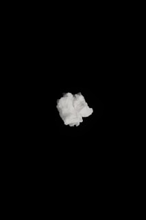 A single crumpled white tissue or paper is centered against a solid black background.