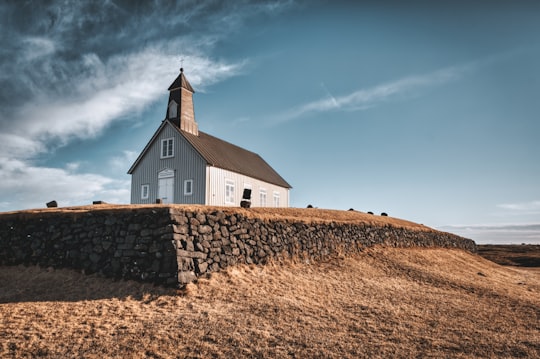white and brown wooden church under blue sky during daytime in Strandarkirkja Iceland