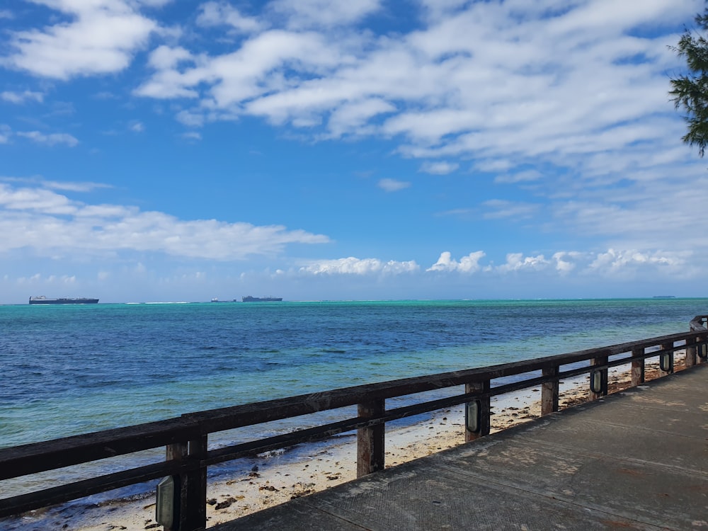 brown wooden dock on blue sea under blue and white cloudy sky during daytime