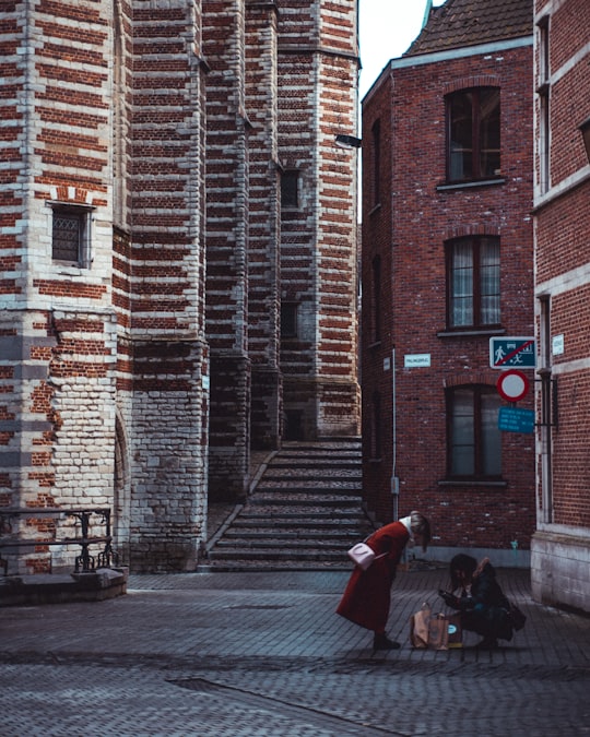 person in red coat walking on sidewalk during daytime in Antwerpen Belgium