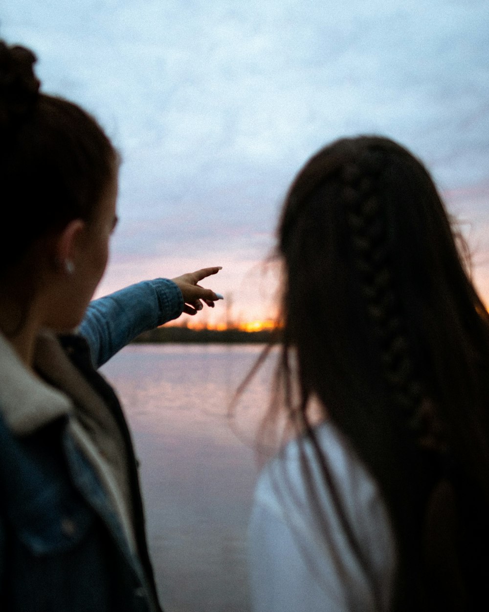 woman in blue denim jacket standing near body of water during daytime