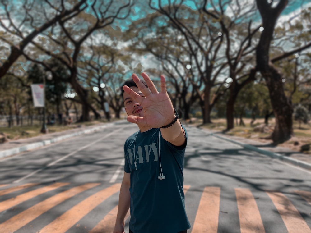 man in blue crew neck t-shirt standing on pedestrian lane during daytime