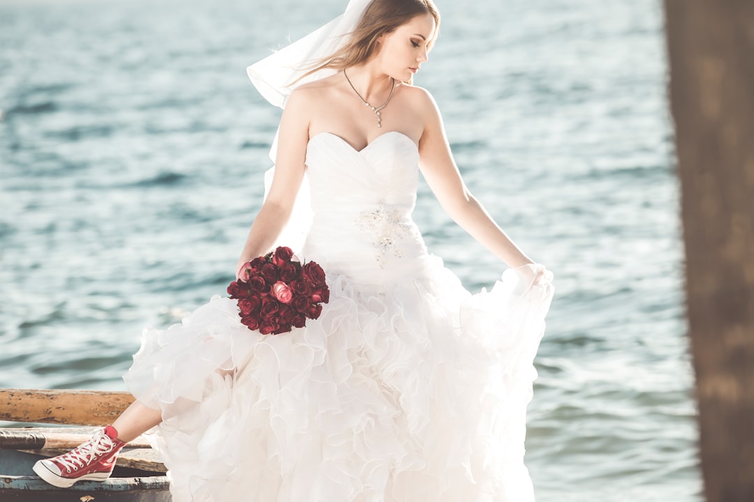 woman in white tube dress holding red rose bouquet