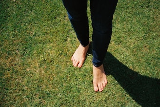 person in blue denim jeans standing on green grass field