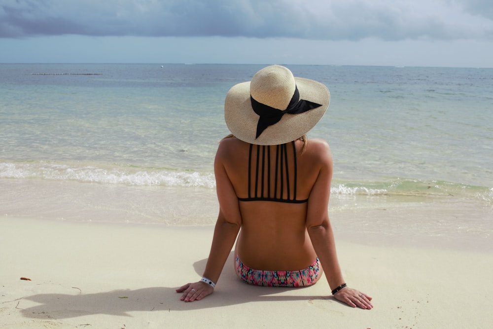 woman in white and black stripe bikini wearing white sun hat standing on beach during daytime