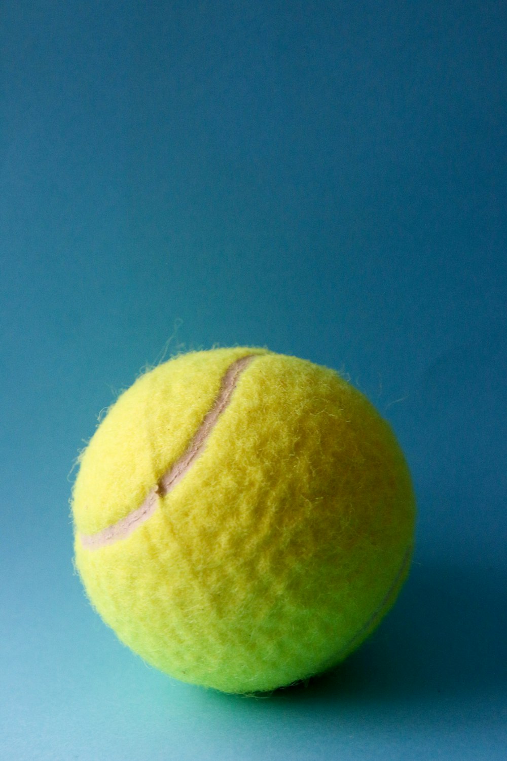 Pelota de tenis verde sobre textil azul