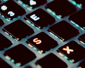 A close-up view of a computer keyboard, focusing on several keys in the top two rows. The keys are black with white letters and numbers, showing some wear and signs of use.
