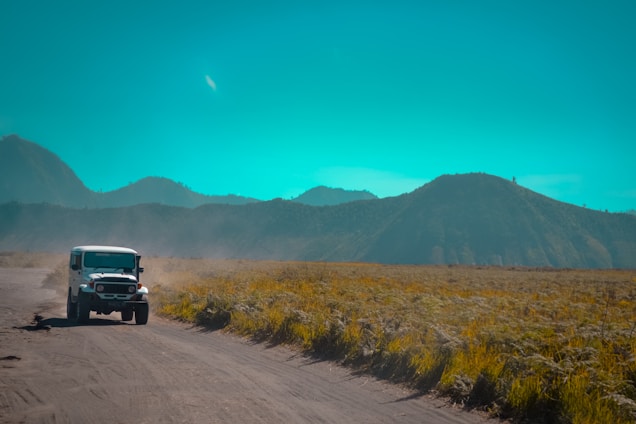 A rugged off-road vehicle navigating a scenic mountain trail under a bright blue sky.