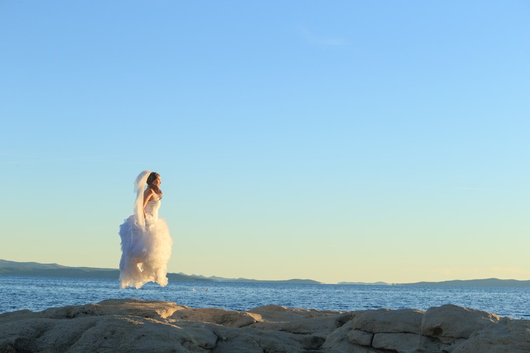 woman in white dress sitting on rock formation during daytime