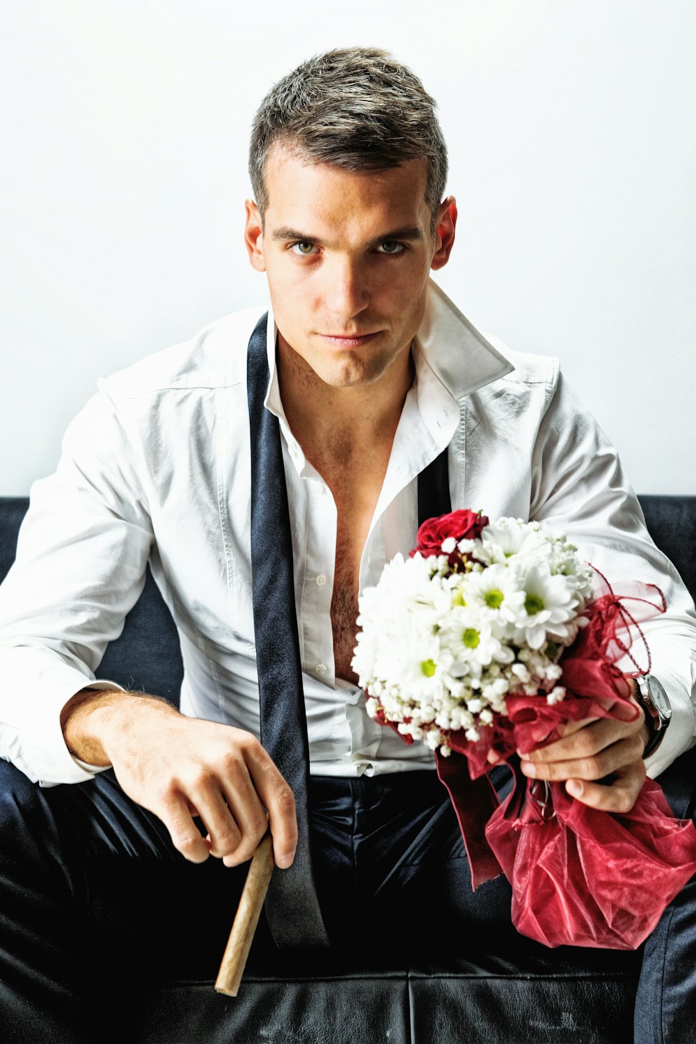 man in white dress shirt holding bouquet of flowers