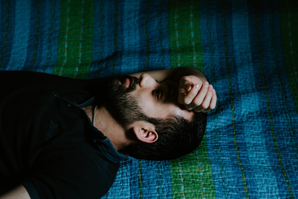 man in black shirt lying on green textile