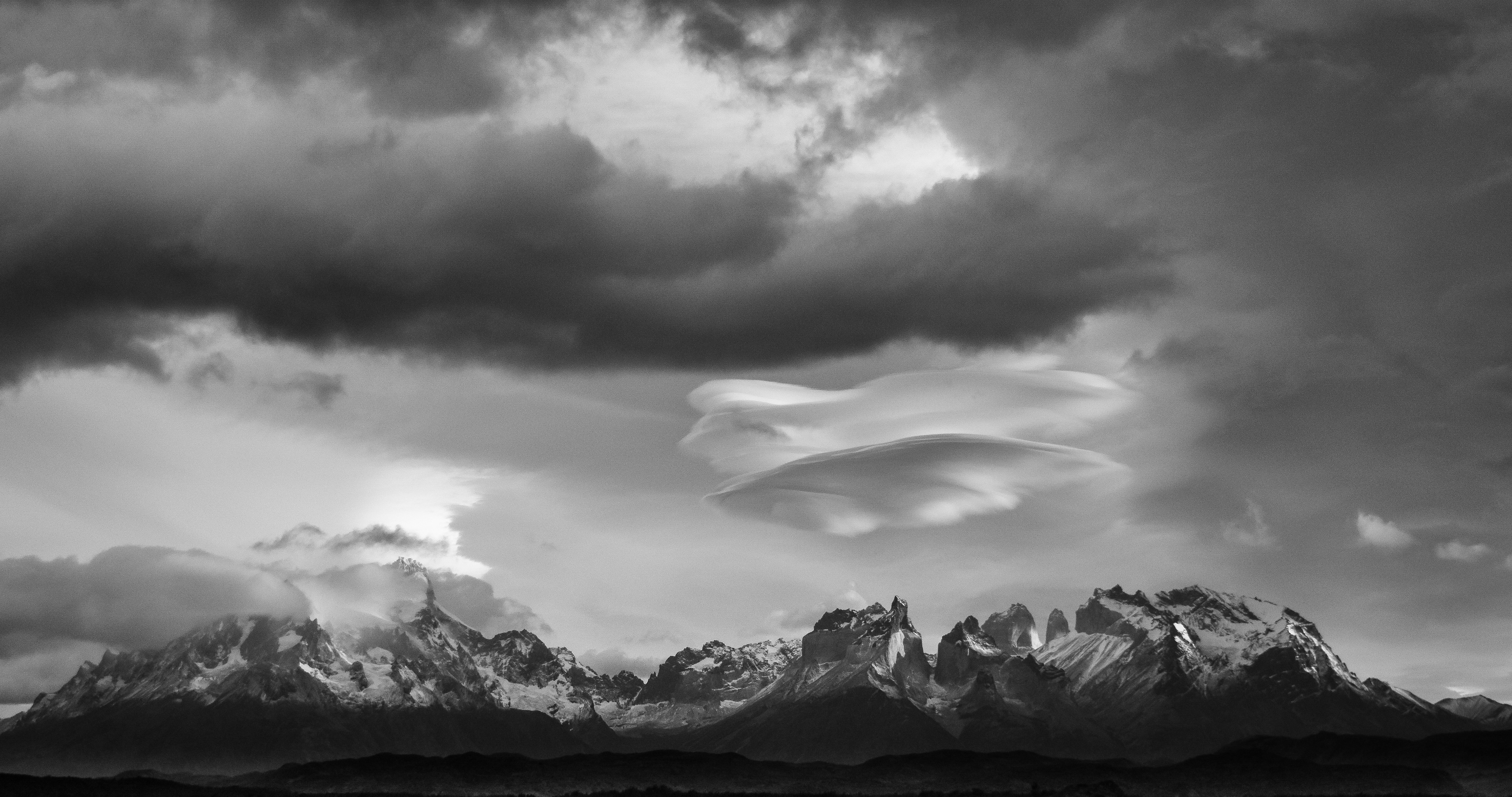 grayscale photo of mountains under cloudy sky