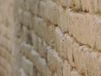 A close-up view of a textured stone wall, showcasing the rough and uneven surfaces of the stones. The image captures the intricate details of the masonry work, with stones stacked in a staggered pattern to form a sturdy structure.