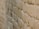 A close-up view of a textured stone wall, showcasing the rough and uneven surfaces of the stones. The image captures the intricate details of the masonry work, with stones stacked in a staggered pattern to form a sturdy structure.