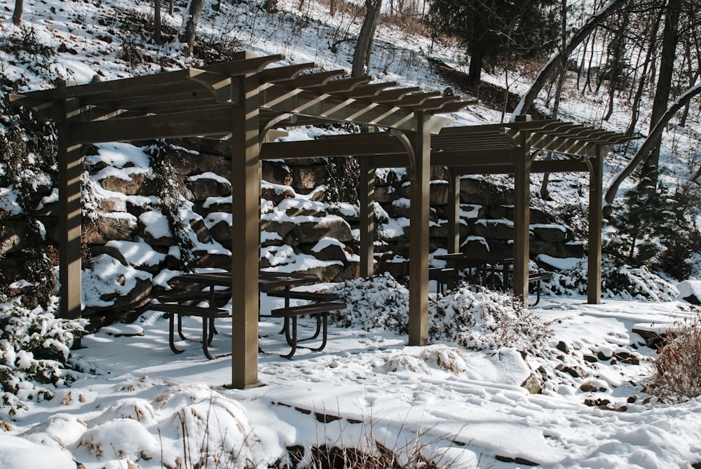 brown wooden gazebo covered with snow during daytime