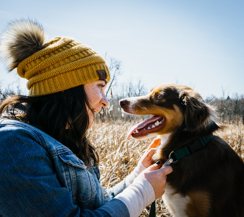 woman in blue denim jacket holding black and white short coat dog