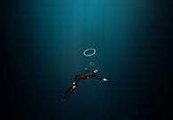 A diver ascending towards the surface with a safety buoy.