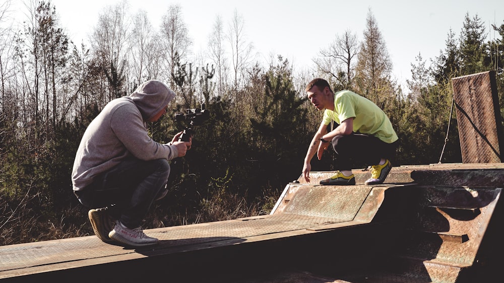 man in green shirt and black pants holding brown wooden board