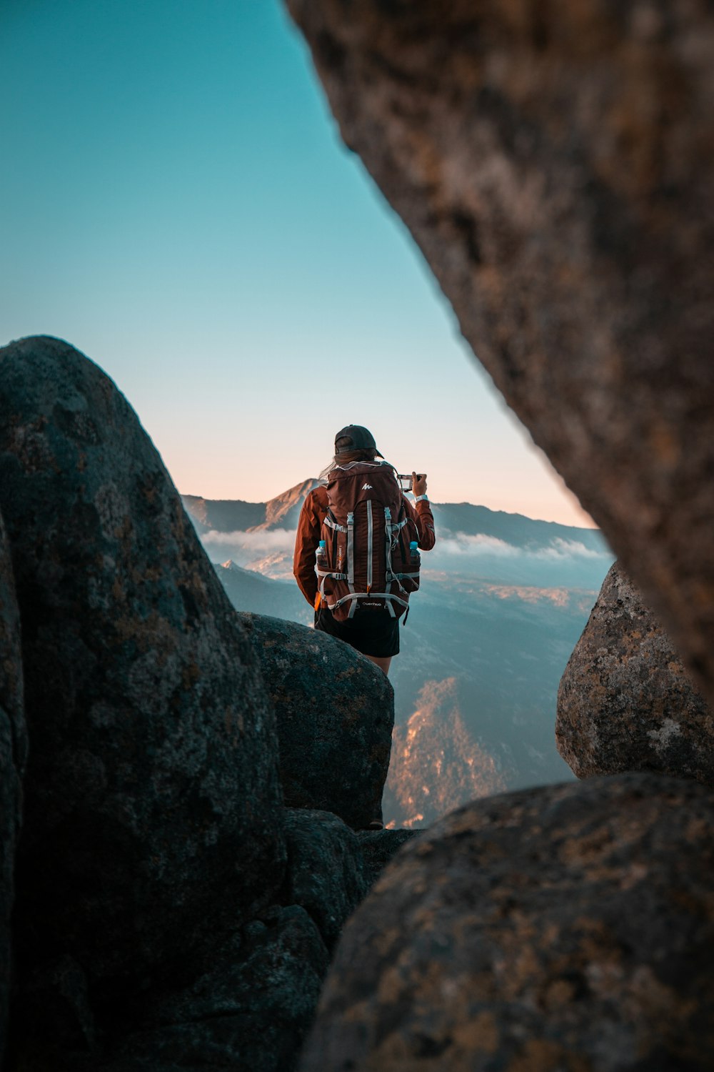 man in black and red backpack standing on rock formation during daytime