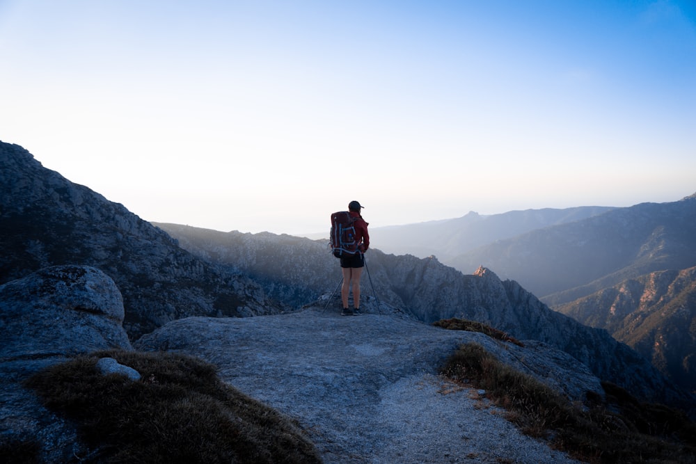 man in black jacket standing on gray rock mountain during daytime