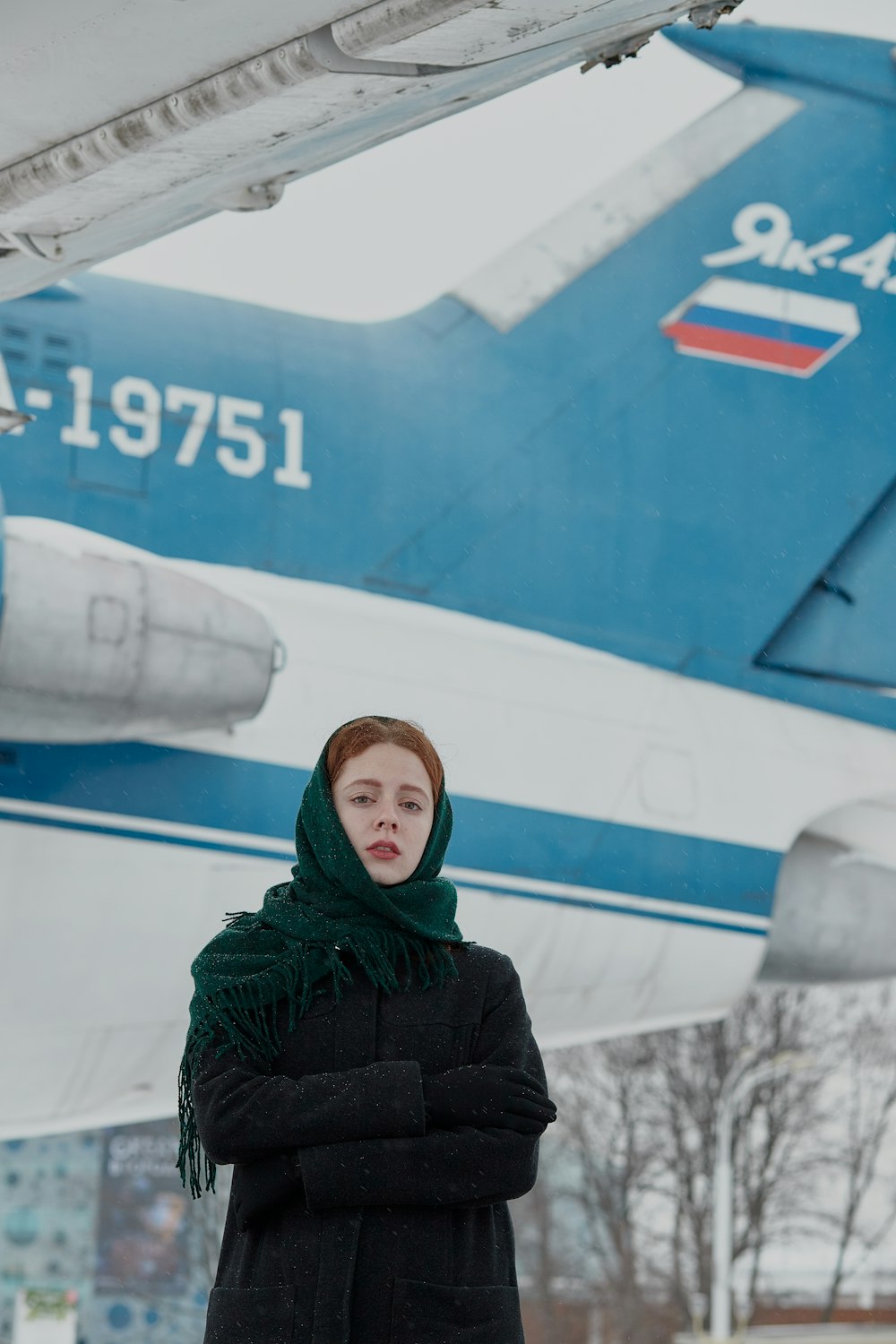 Frau in schwarzer Jacke steht in der Nähe eines weißen Flugzeugs