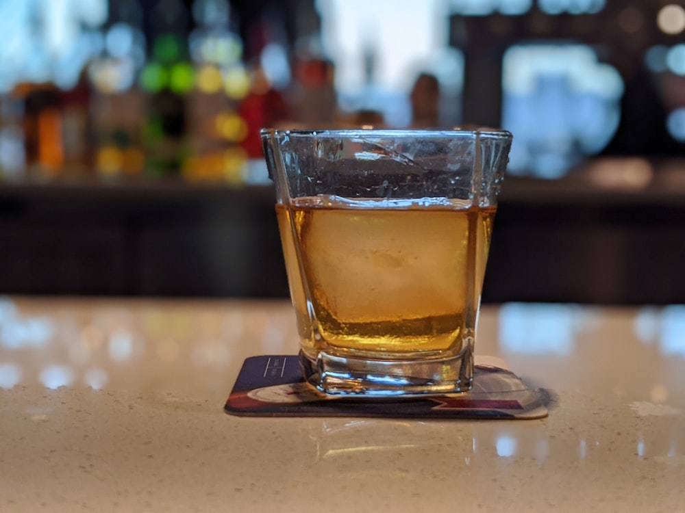 clear shot glass with brown liquid on brown wooden table