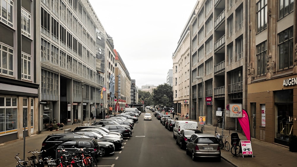 cars parked on the side of the road in between buildings during daytime