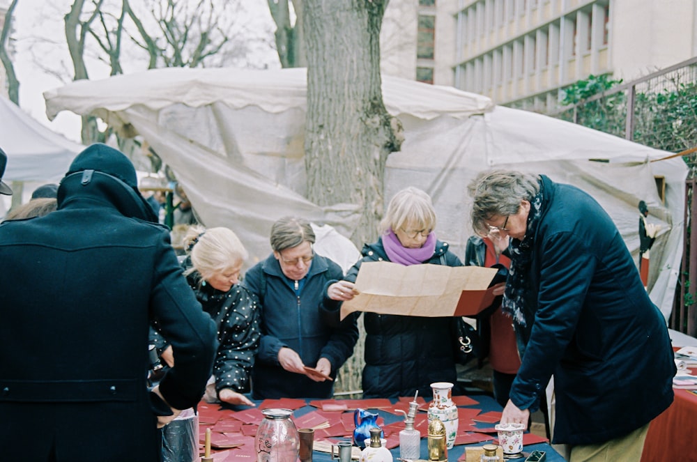 people gathering around table with red and white table cloth during daytime