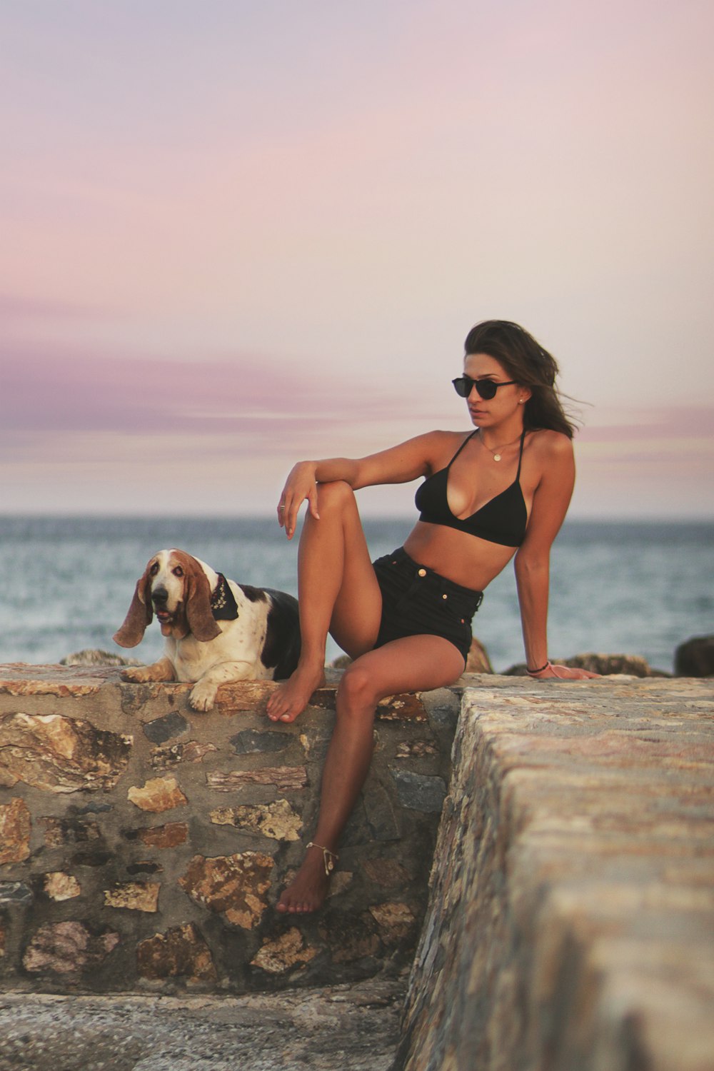 femme en bikini noir assis sur le rocher près de la mer pendant la journée