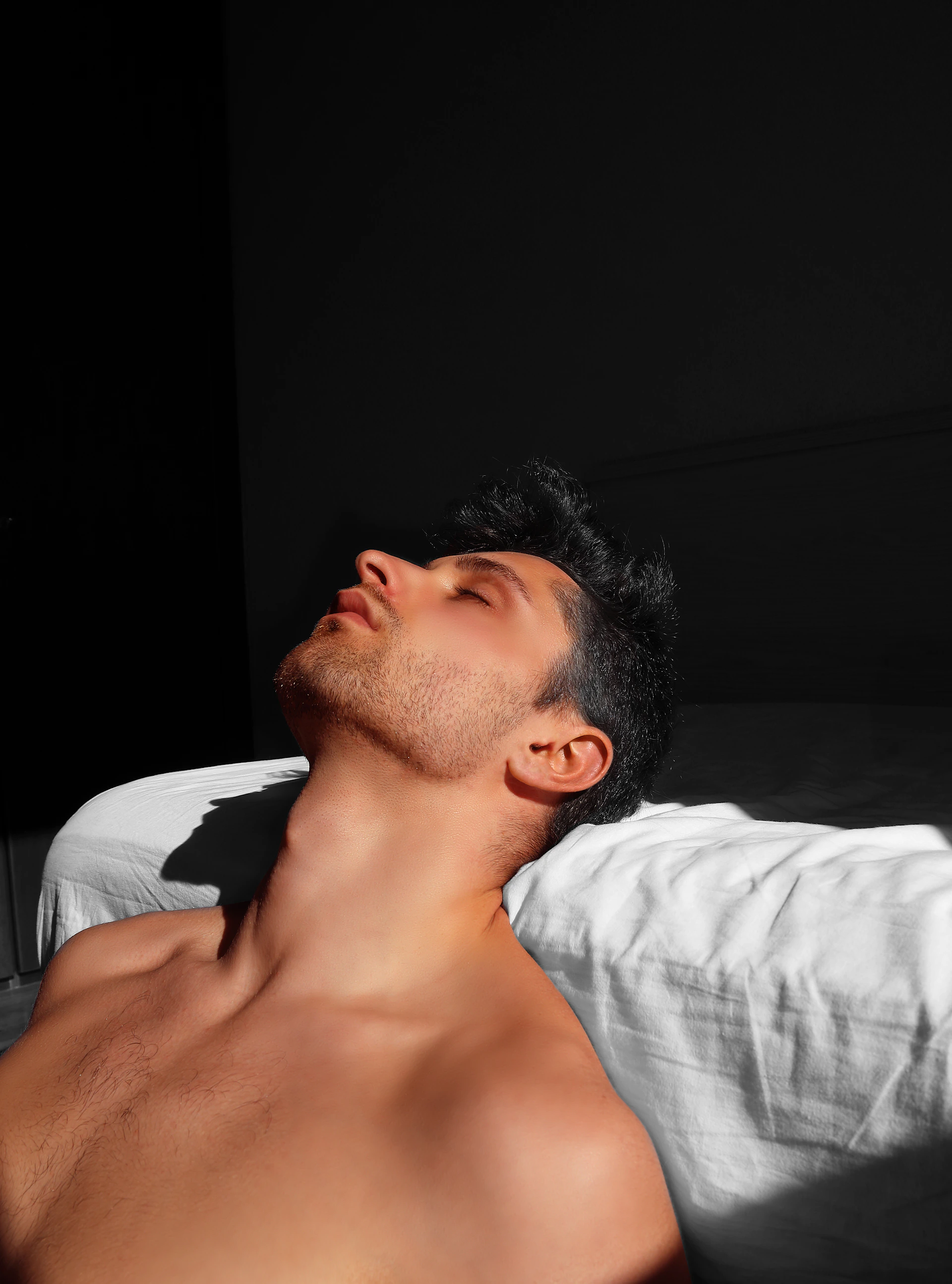 Man resting with eyes closed on a white pillow.
