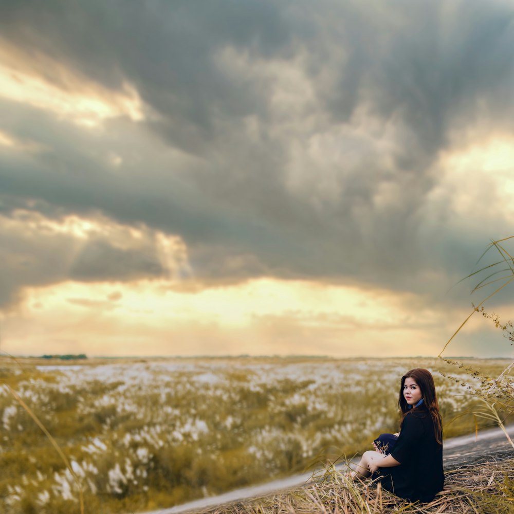 woman in black jacket sitting on gray metal railings during daytime