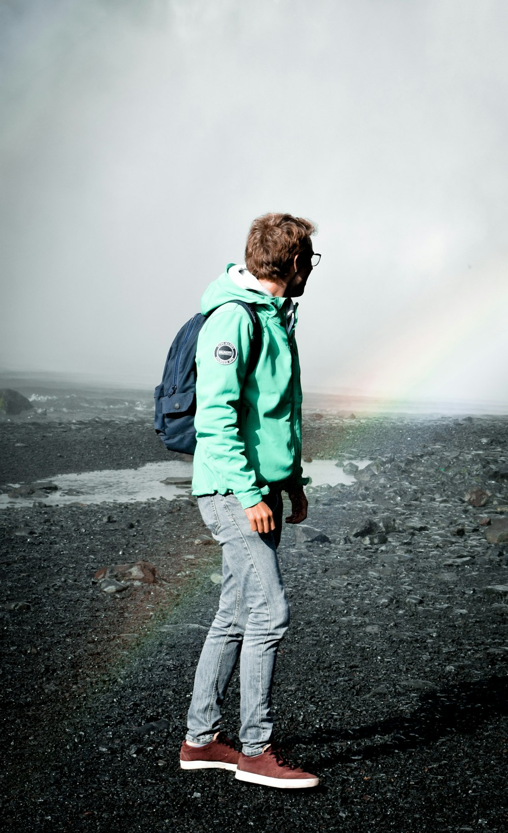 man in green jacket walking on gray sand during daytime