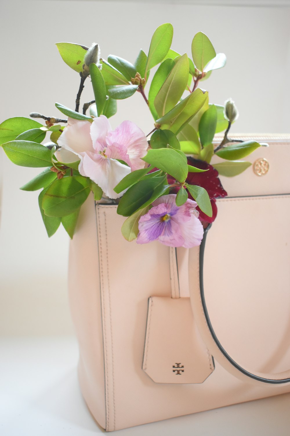 pink and white flowers on white leather handbag