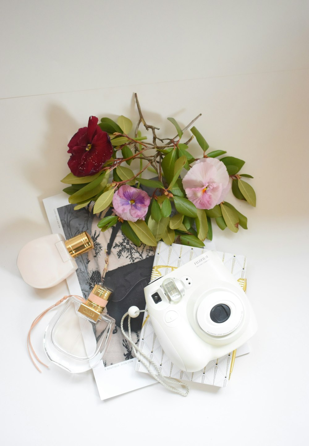 pink and white roses in vase beside white camera