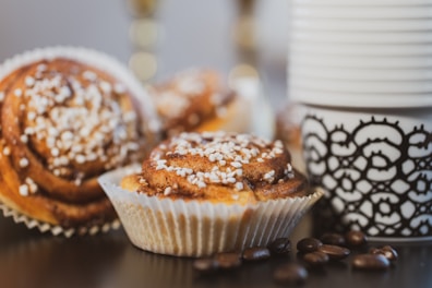 A steaming cup of coffee next to a cinnamon roll.