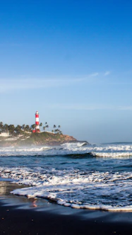 red and white lighthouse on rock formation near sea during daytime