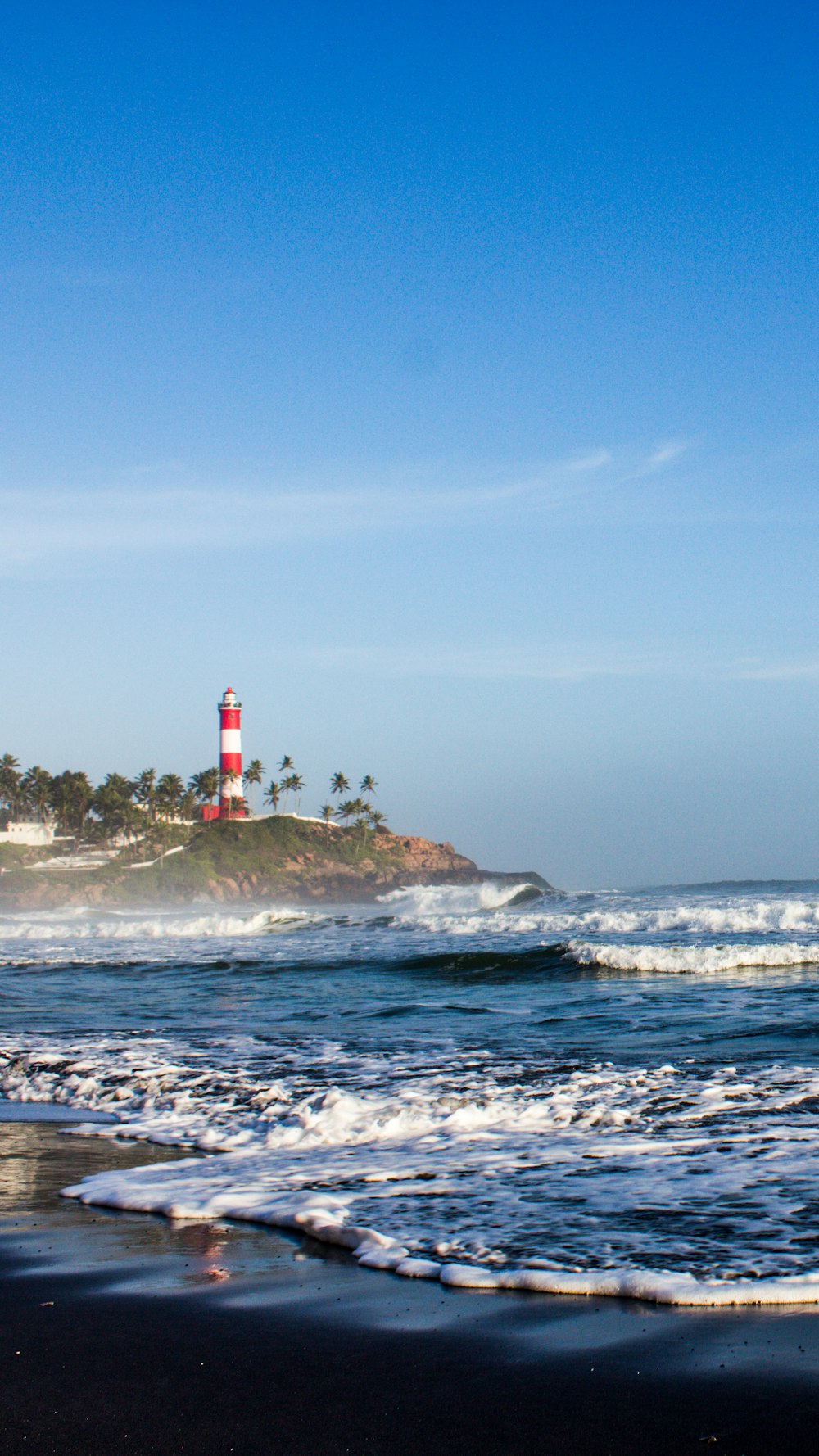 red and white lighthouse on rock formation near sea during daytime