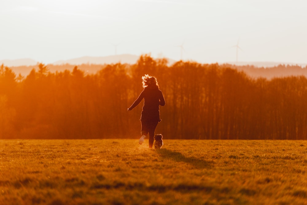 girl in black jacket and pants running on green grass field during daytime