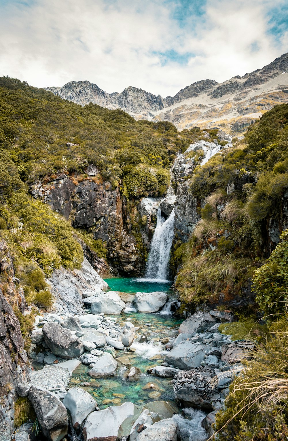 green and brown mountain beside river during daytime