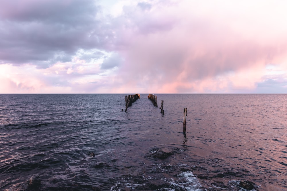 3 person standing on sea shore during daytime