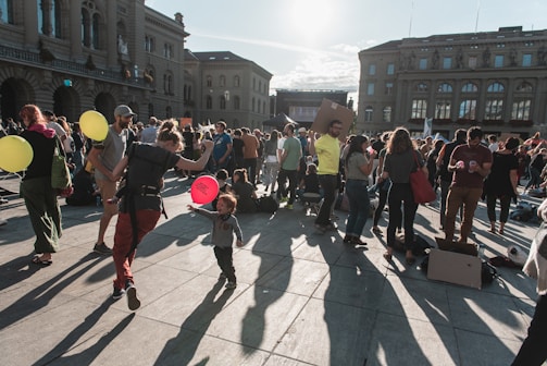 A lively community meeting in a sunny Lithuanian town square with diverse locals engaged in lively discussion.