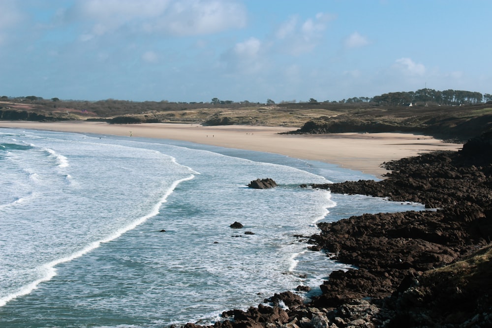 body of water near brown sand under blue sky during daytime