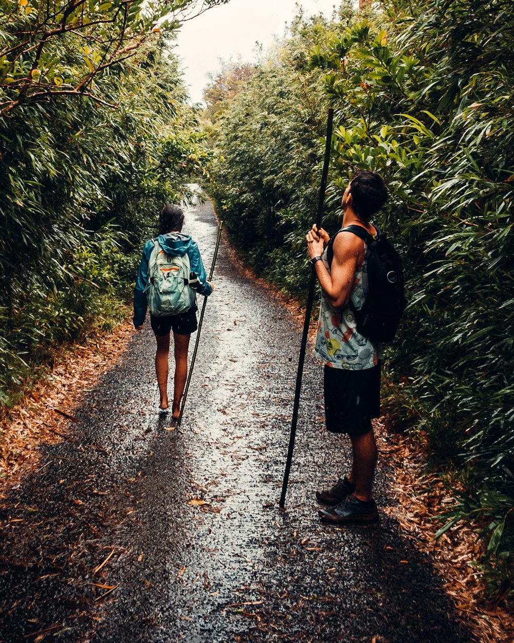 man in blue t-shirt and black shorts walking on dirt road