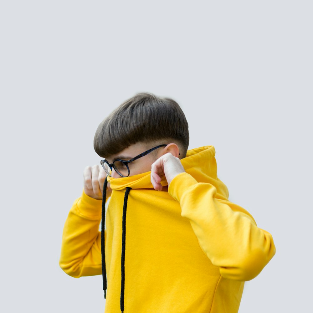 Junge in gelbem Kapuzenpulli, der sein Gesicht bedeckt