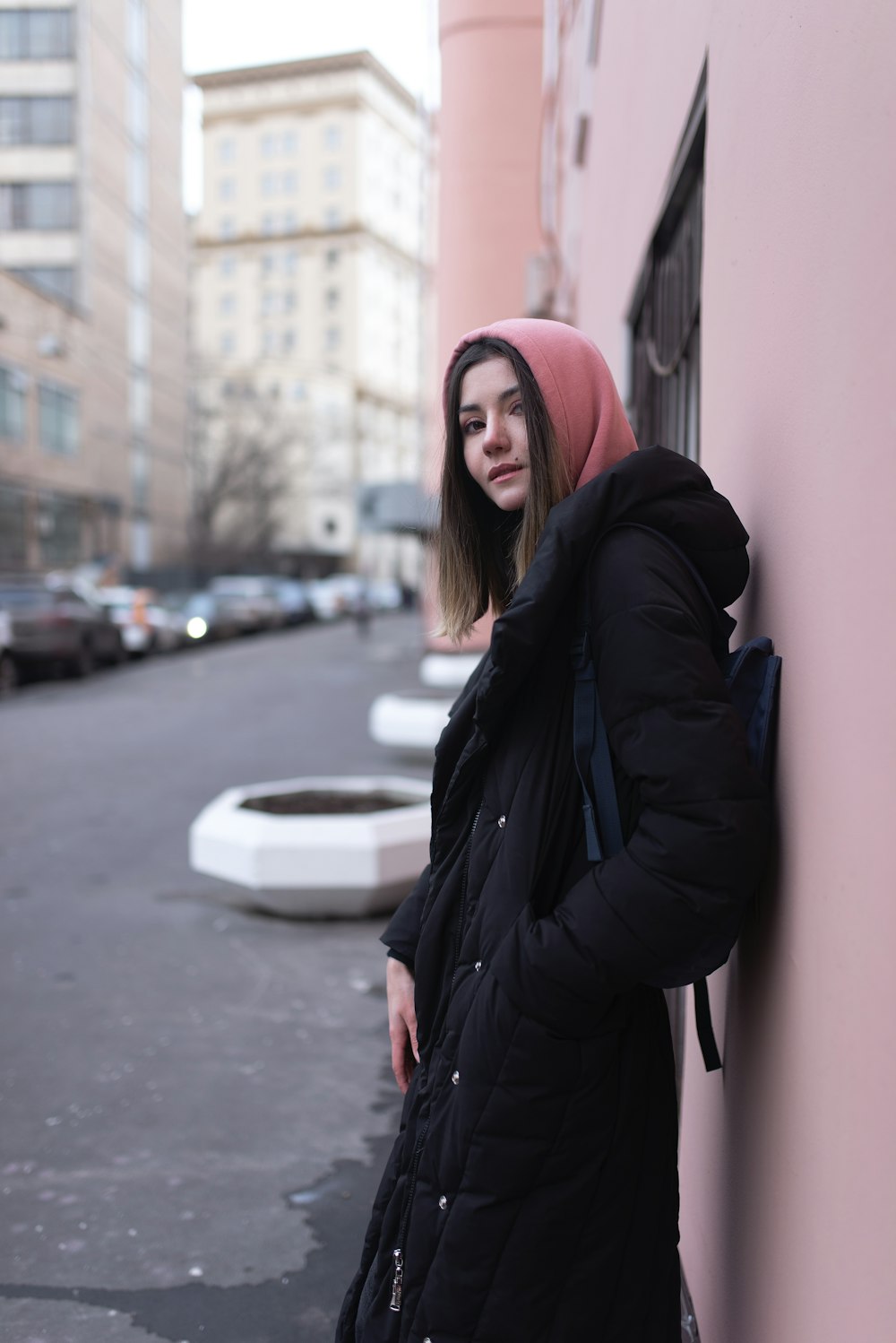 woman in black jacket and red knit cap standing near white car during daytime