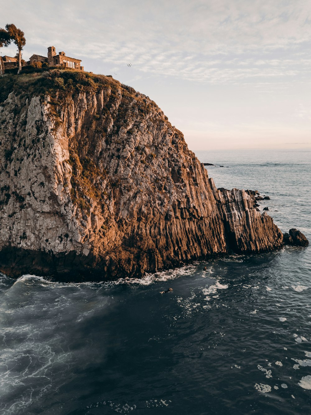 Formación rocosa marrón junto al cuerpo de agua durante el día