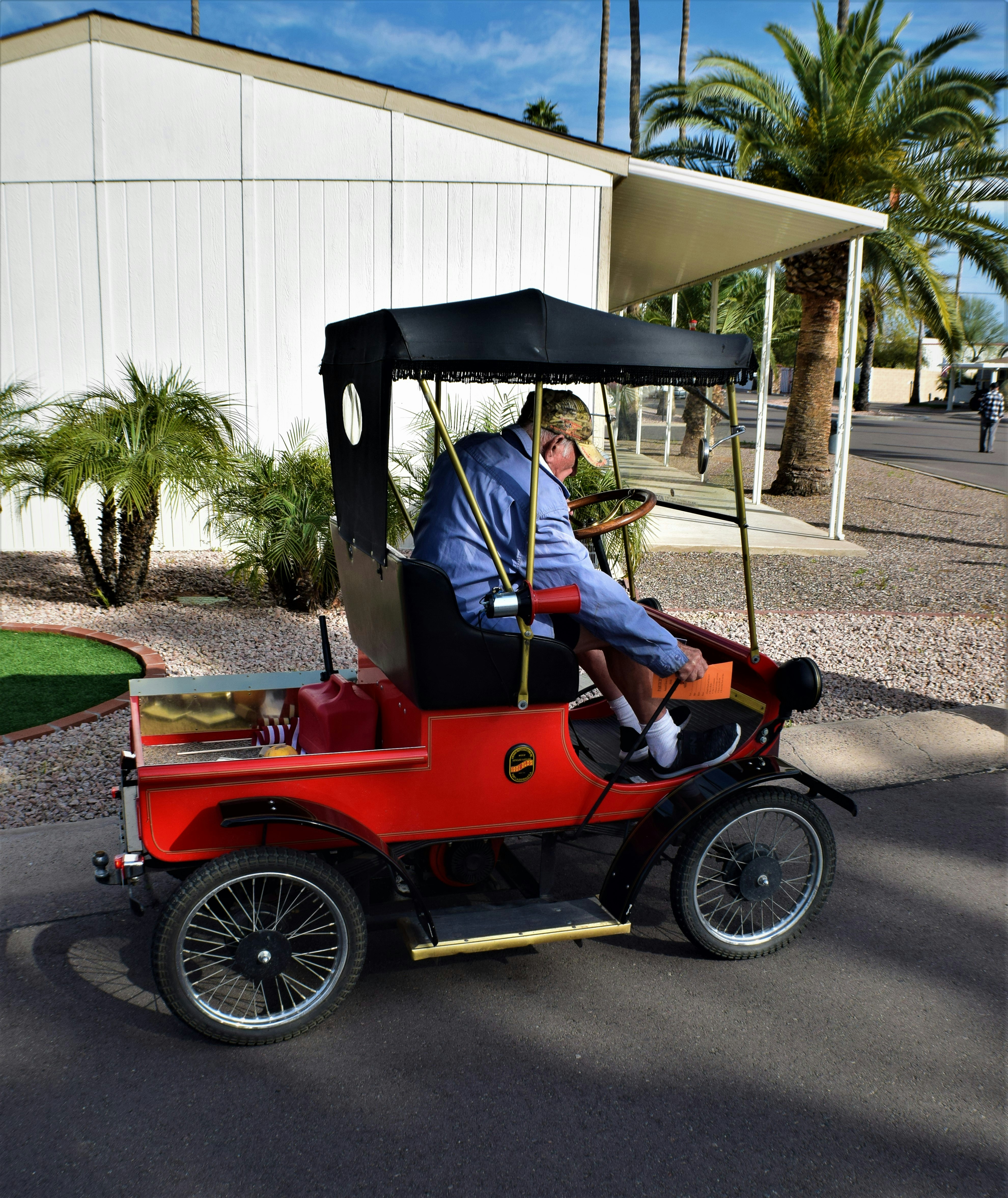 man in blue jacket riding red and black vintage car during daytime