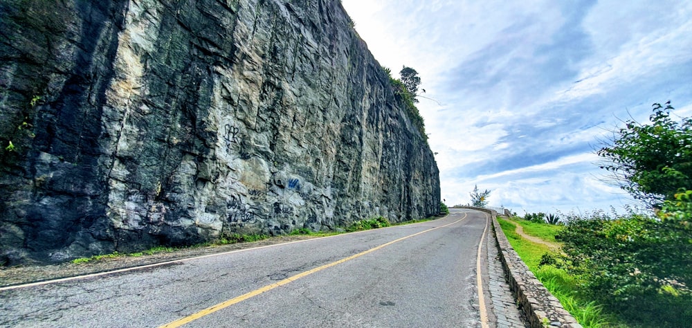 gray concrete road between gray rocky mountain during daytime